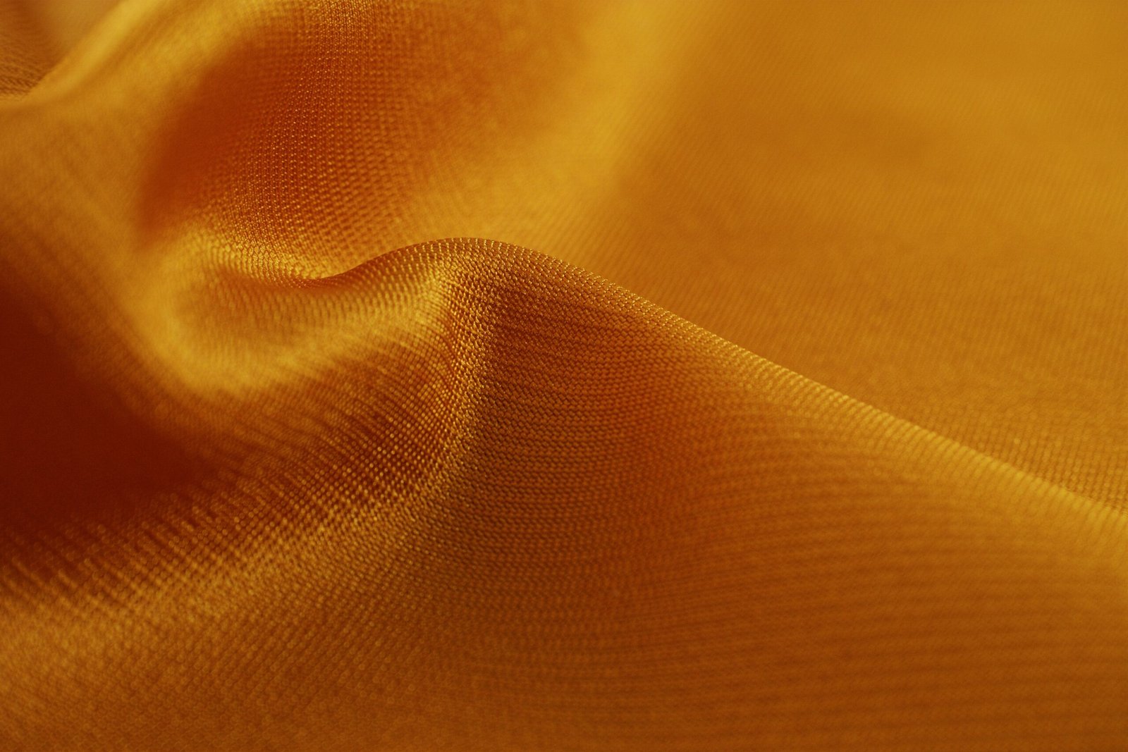 Close-up of natural silk fabric showing deep golden luster and soft flowing texture